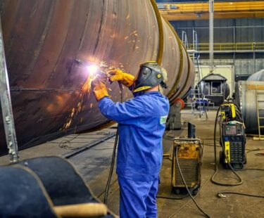 A welder processing a black steel tank at the Ekonstal production plant in Piotrków Kujawski